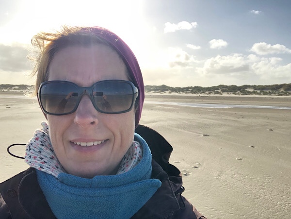 Selfie von Frau mit Mütze und Sonnenbrille am Strand