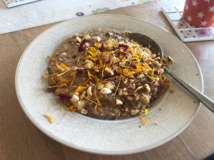 Ein Teller mit Porridge, mit gehackten Nüssen und Blütenblättern bestreut