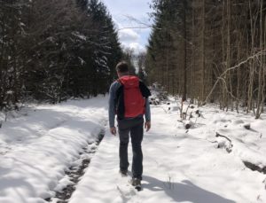 Mann mit Rucksack wandert im Schnee im Wald